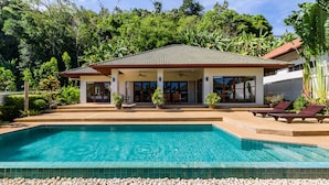 Blick auf ein Haus mit Pool, ein Poolblick, das ein Haus mit einem Ziegeldach und einer überdachten Terrasse zeigt.