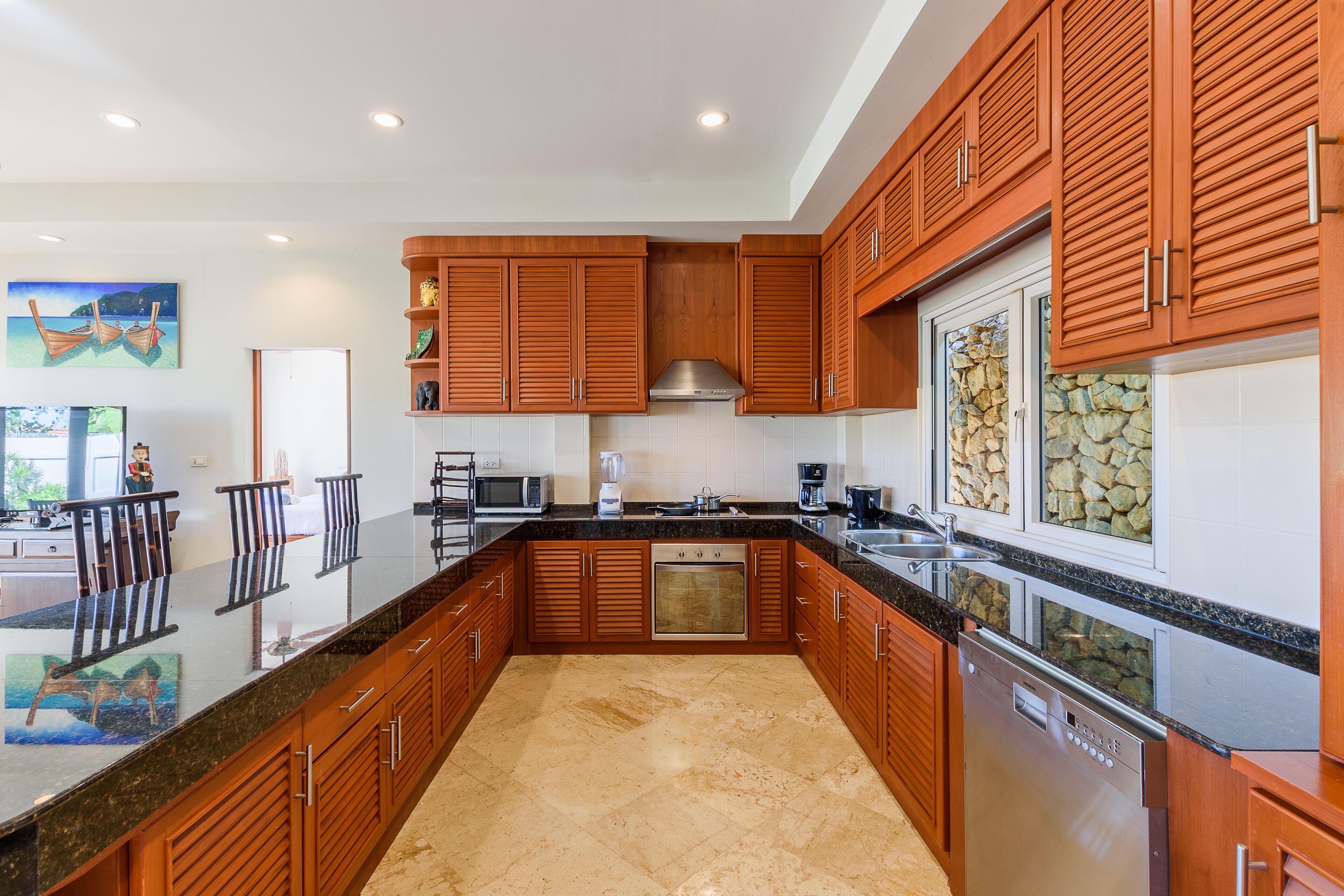 A modern kitchen with wooden cabinets, a stainless steel dishwasher, and a granite countertop.