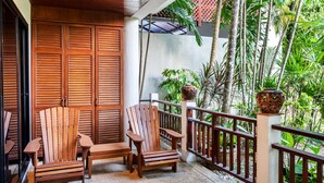 A wooden deck with two chairs and a table, surrounded by a wooden fence and lush greenery. - The Sands 2 bedroom apartment (Rawai)