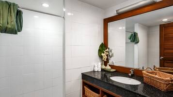 A bathroom with white tiles, a black sink, a mirror, and wicker baskets.
