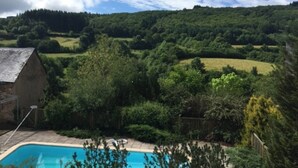 A swimming pool surrounded by lush greenery and a hill in the background. - Would you like to let your mind wander? Welcome to the Morvan Nature Park (Cussy-en-Morvan)