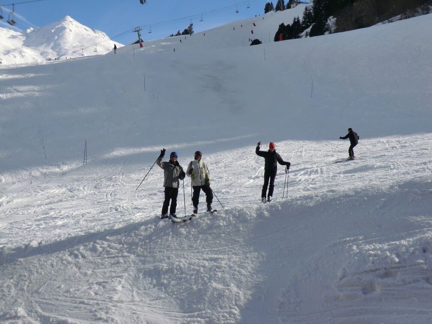 Pista de esqui coberta de neve, com esquiadores e um teleférico ao fundo.