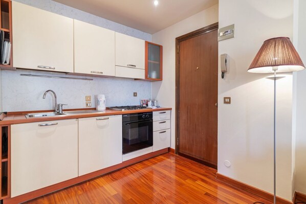 Una cocina moderna con armarios blancos, encimera de madera, estufa y lavaplatos.