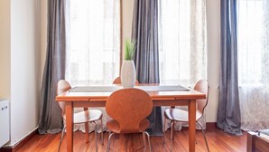 A dining area with a wooden table, four chairs, and a vase of greenery.