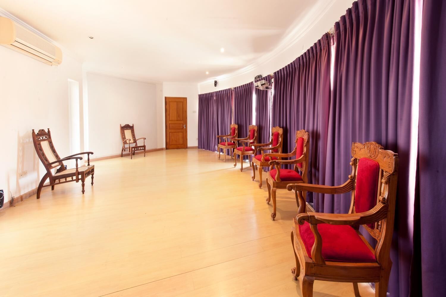 Una habitación con sillas de madera y una silla de madera con cojín rojo.