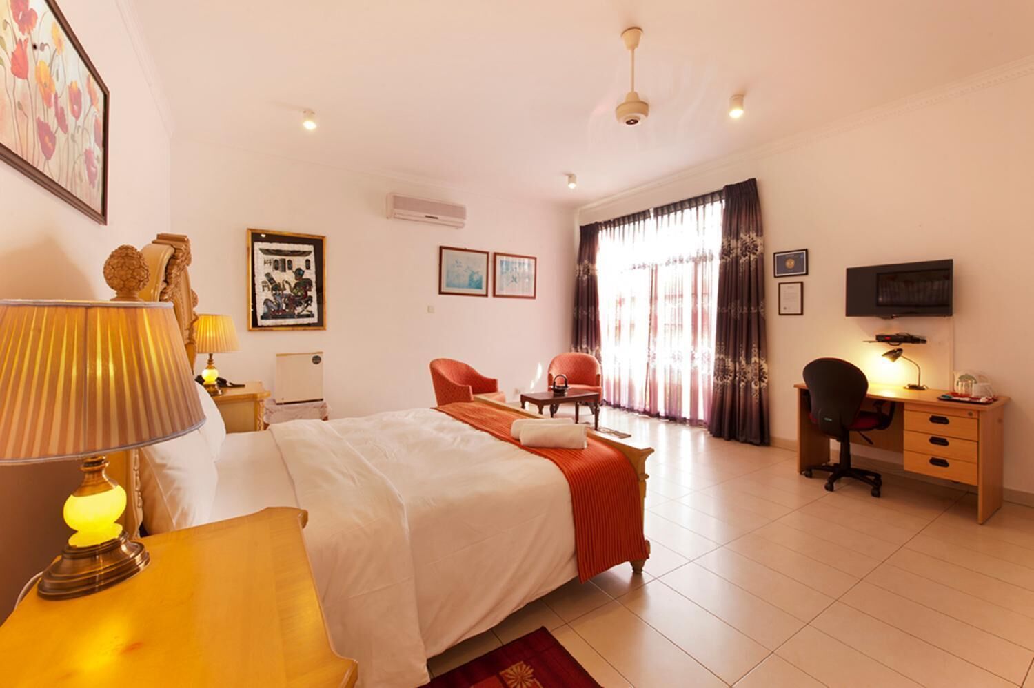 A hotel room with a bed, desk, chair, and a television.