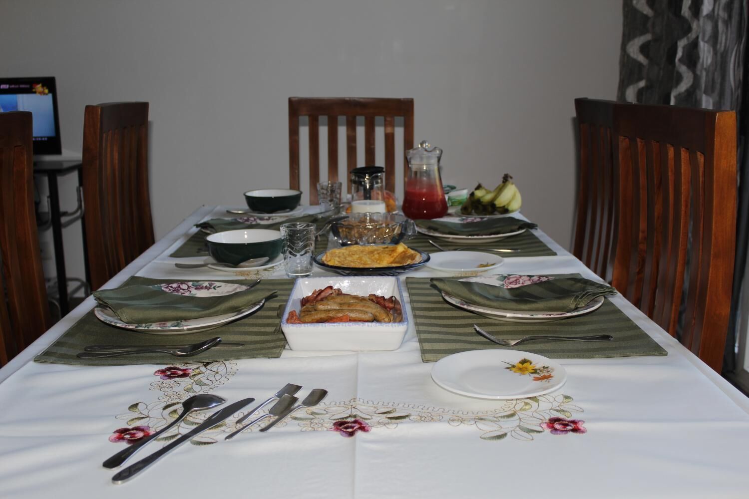 Una mesa lista para comer, con platos, cubiertos y un plato de comida.