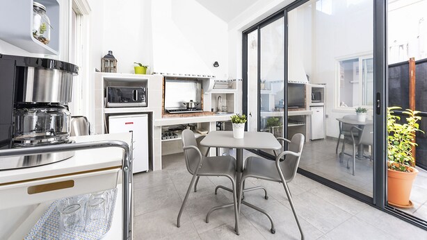 A modern kitchen with a dining area, large windows, and a view of the outdoors. - STUDIO ZEN Gare St Jean (Bordeaux)