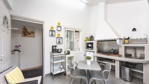 A compact kitchen with a dining area, featuring a white color scheme, a small dining table, and a built-in stove. - STUDIO ZEN Gare St Jean (Bordeaux)