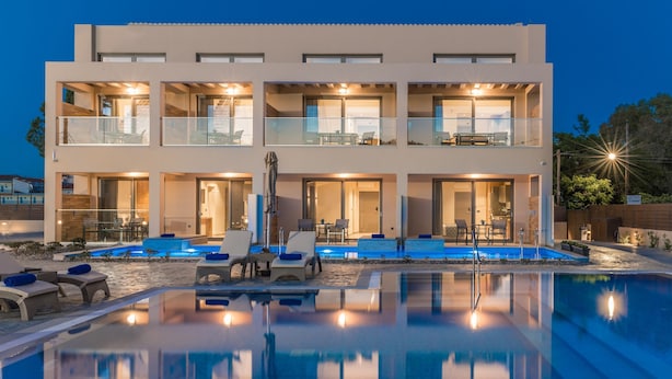 A modern two-story building with a swimming pool, outdoor seating, and multiple balconies.