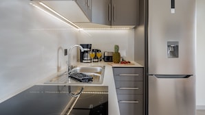 A modern kitchen with stainless steel appliances, a built-in sink, and a countertop with a coffee maker and fruit.