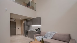 A modern apartment with a kitchenette, a sofa, and a coffee table with fruit.