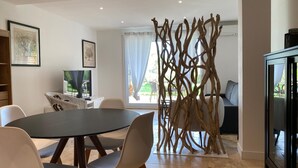 A modern dining area with a round table, white chairs, and a decorative wooden partition. - B&B Mas Lou Felibrige (Venelles)