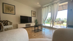 A living room with a flat-screen TV, a cactus, and a dining area with outdoor seating. - B&B Mas Lou Felibrige (Venelles)