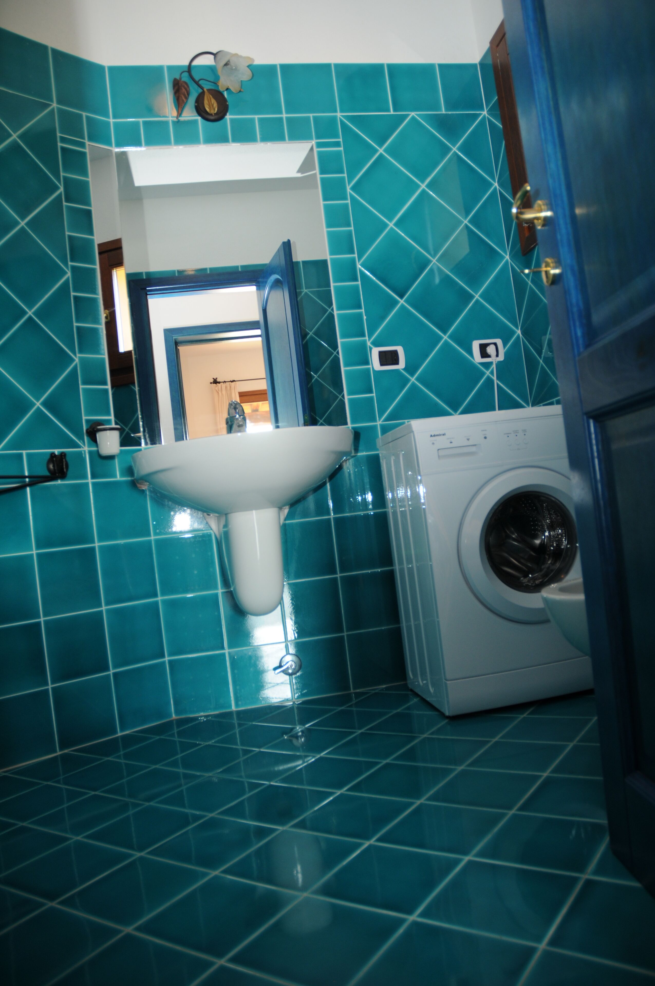 A bathroom with a sink, a washing machine, and a mirror.