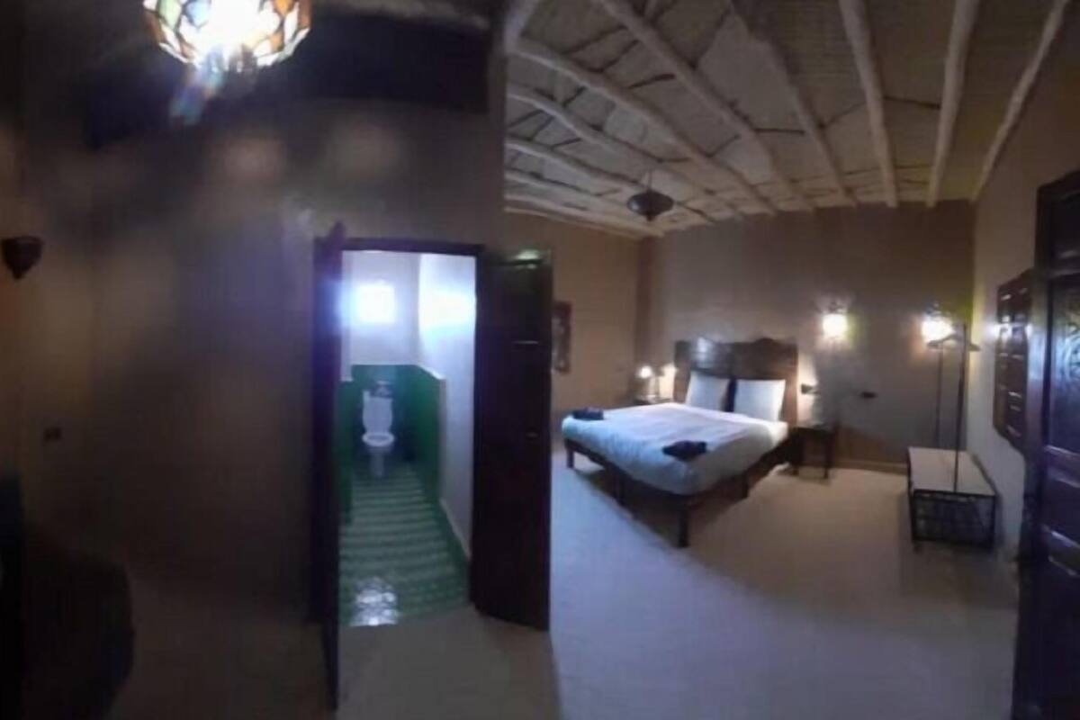 A hotel room with a bed, bedside table, and a small seating area.