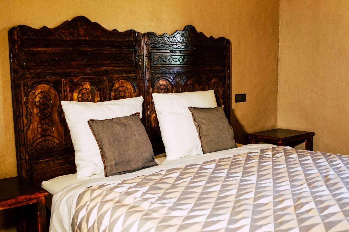 A bed with a patterned bedspread, two pillows, and a wooden headboard.