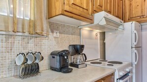 Una cucina con mobili in legno, una macchina da caffè, un fornello e una rastrelliera per pentole.