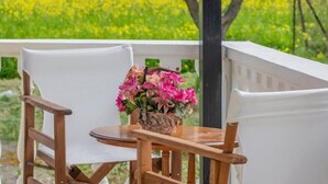 Una sedia e un tavolo di legno su un balcone con vista su un campo giallo.
