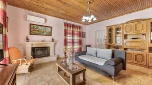 Un accogliente soggiorno con camino, un divano, un mobiletto in legno e un soffitto con travi in legno.