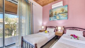 Una camera da letto con due letti, un quadro appeso e un balcone con vista.