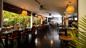 Un restaurante con mesas, sillas y luces colgantes, con espacio interior.