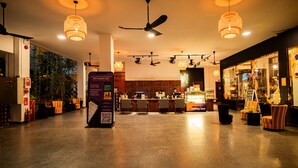 Un vestíbulo amplio con mostrador de recepción, zona de estar y vista a la cocina al fondo.