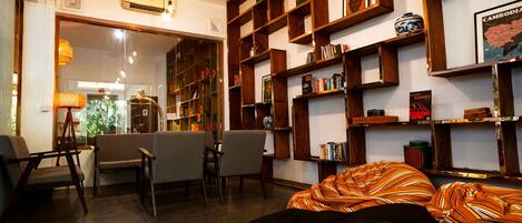 A cozy living room with a sofa, chairs, and a bookshelf filled with books and decorative items.