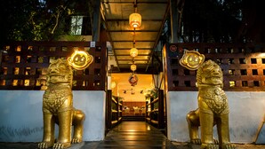 Un sendero bordeado por estatuas de leones dorados que conduce a un edificio con un cartel que indica arquitectura del siglo XVIII.