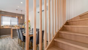 Une cuisine moderne avec des meubles en bois, un coin repas comprenant une table et des chaises, et un escalier en bois.
