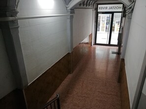 A hallway with a white wall and a brown floor leading to a door labeled 'HOSPITAL VETERINARIAN'. - Hostal River (Barcelona)