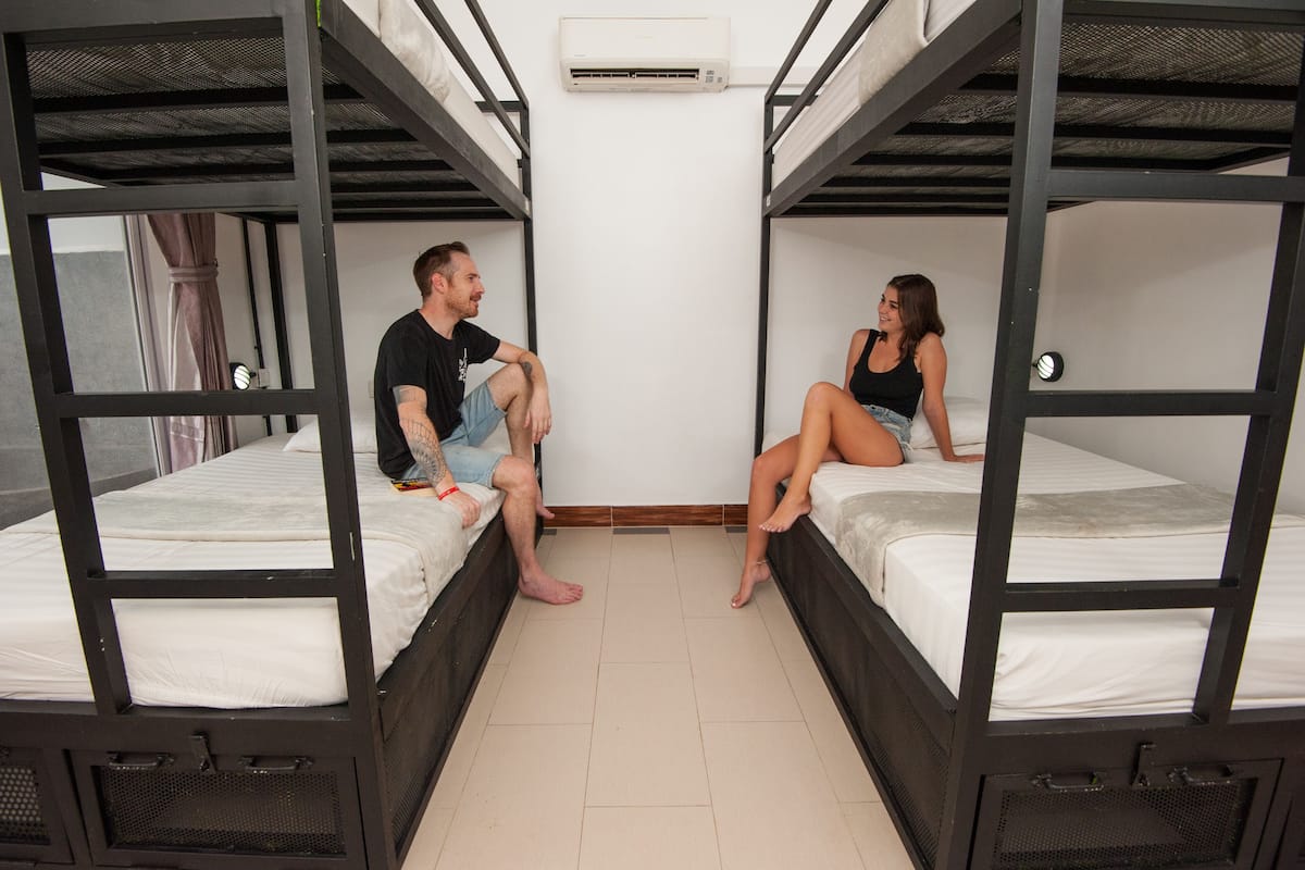 Un dormitorio con literas, un equipo de aire acondicionado blanco y suelo de baldosas.