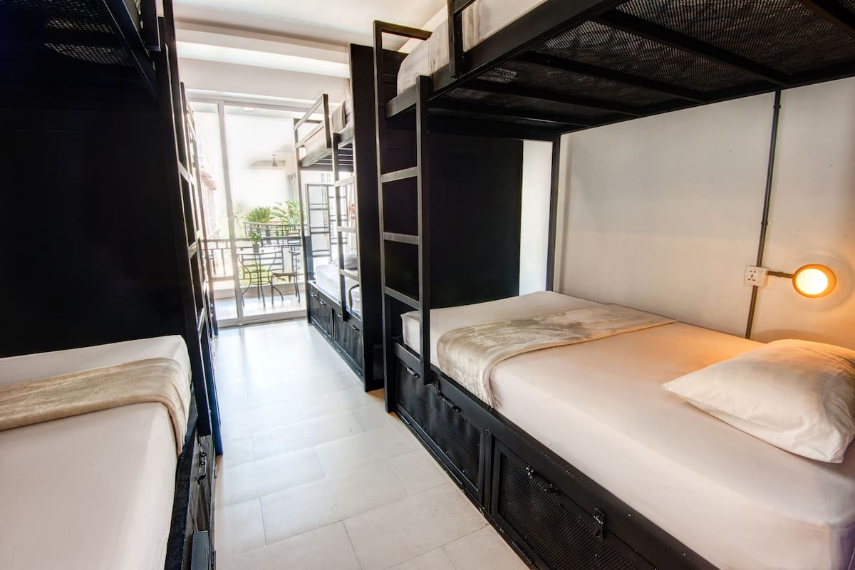 Un dormitorio con literas, un balcón con plantas y una lámpara de pared.