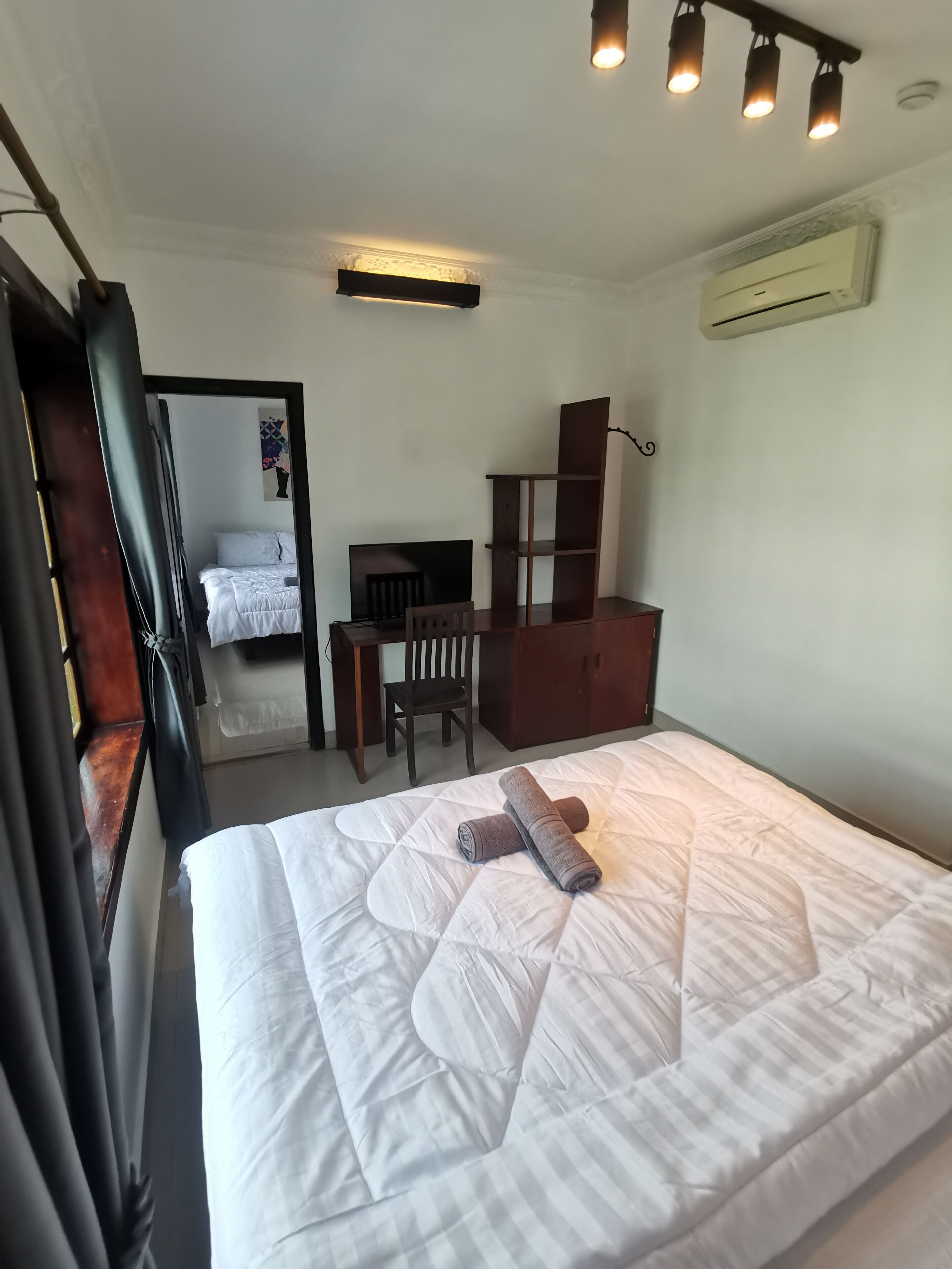 A bedroom with a bed, a wooden chair, a desk, and a wardrobe.