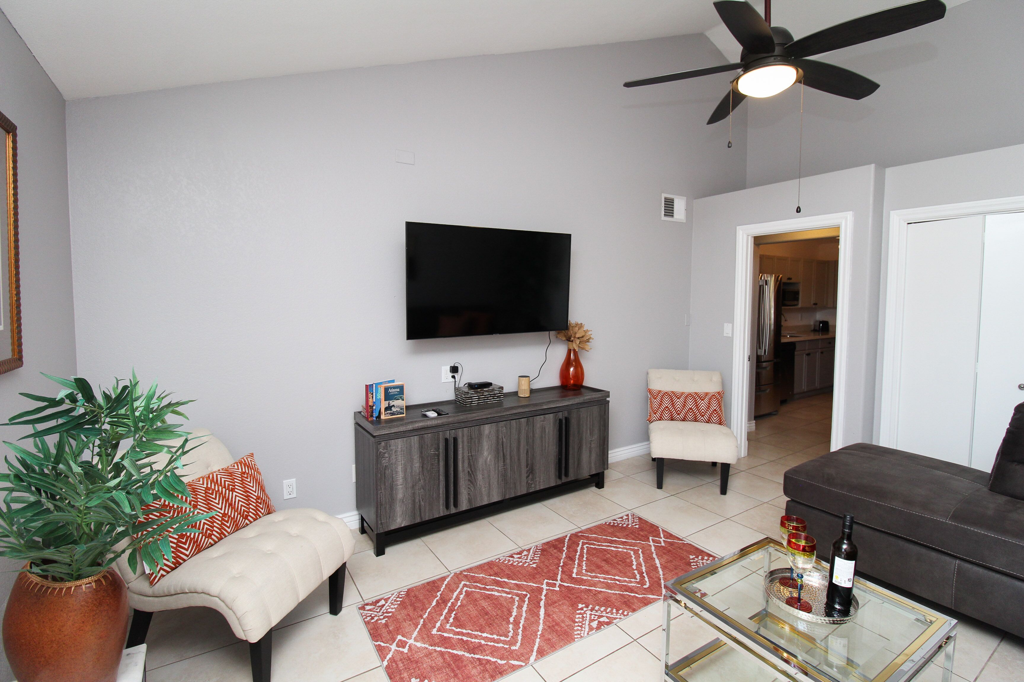 A living room with a TV, sofa, armchair, and a coffee table.