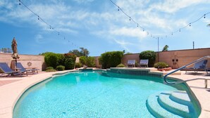 Une piscine aux eaux cristallines, dotée de chaises longues et d’un petit espace aménagé en terrasse.