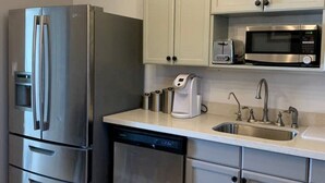 Une cuisine moderne équipée d’appareils électroménagers en acier inoxydable, d’un lave-vaisselle, d’un four à micro-ondes et d’un évier.