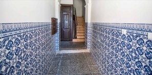 Staircase leads to a door at the end of a hallway with a blue and white tile pattern.