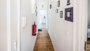 Un pasillo estrecho con suelo de madera, paredes blancas y varias fotografías enmarcadas.