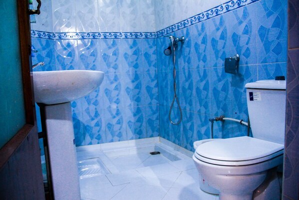 Un baño con lavamanos, inodoro y ducha blancos.