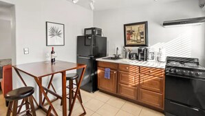 Een moderne keuken met een eethoek, met een koelkast, fornuis en barstoelen.