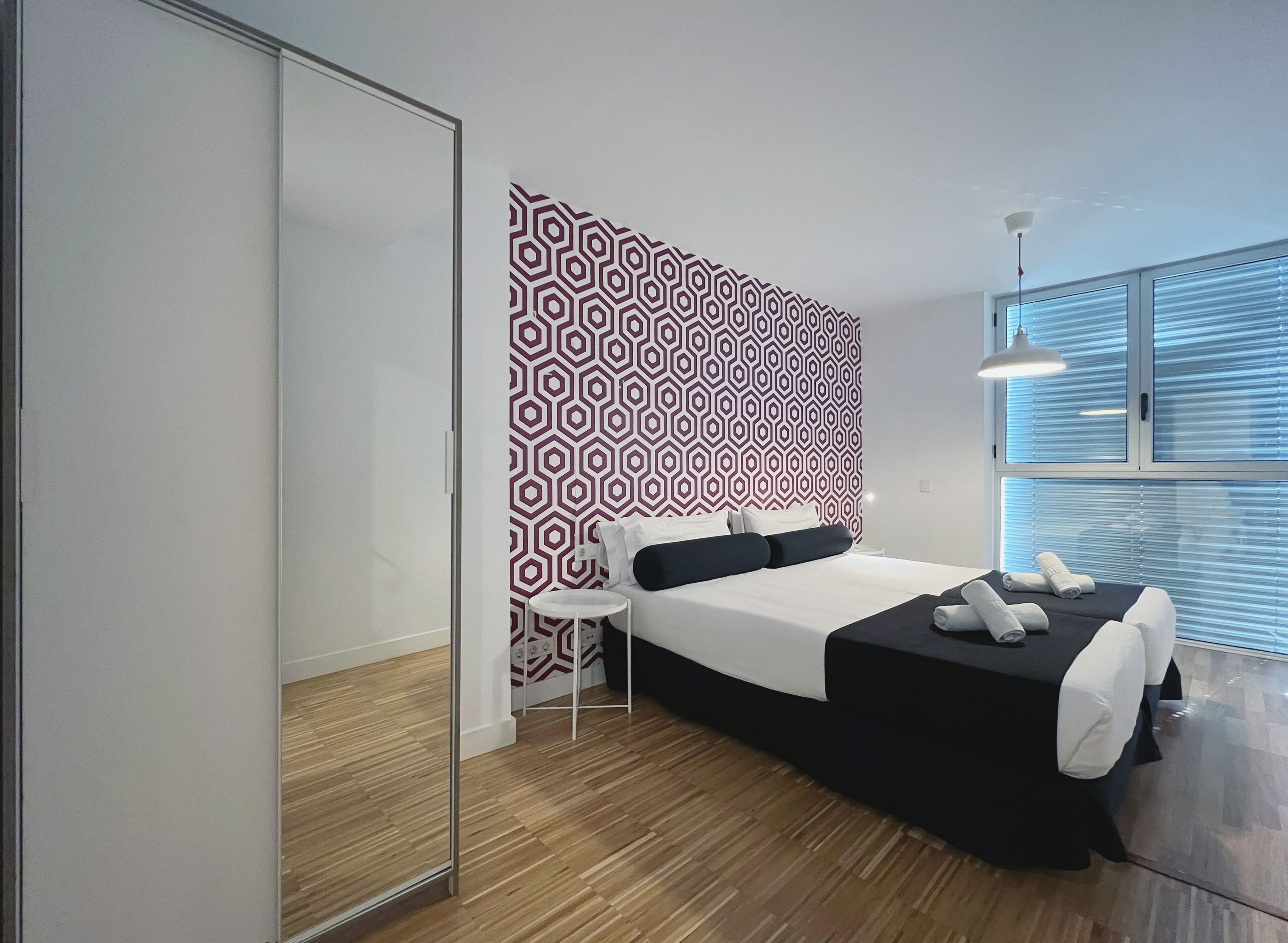 Een moderne hotelkamer met een bed, een tafeltje, een spiegel en een kamer met een patroon op de muur.