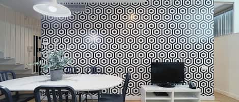 Un comedor moderno con una pared de diseño geométrico, una mesa redonda y sillas negras.
