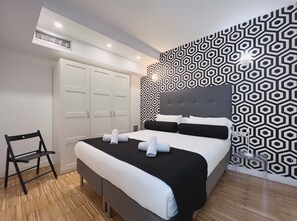 A modern hotel room with a bed, a wardrobe, a chair, and a patterned wall. - Stay U-nique Apartments Pellaires (Barcelona)