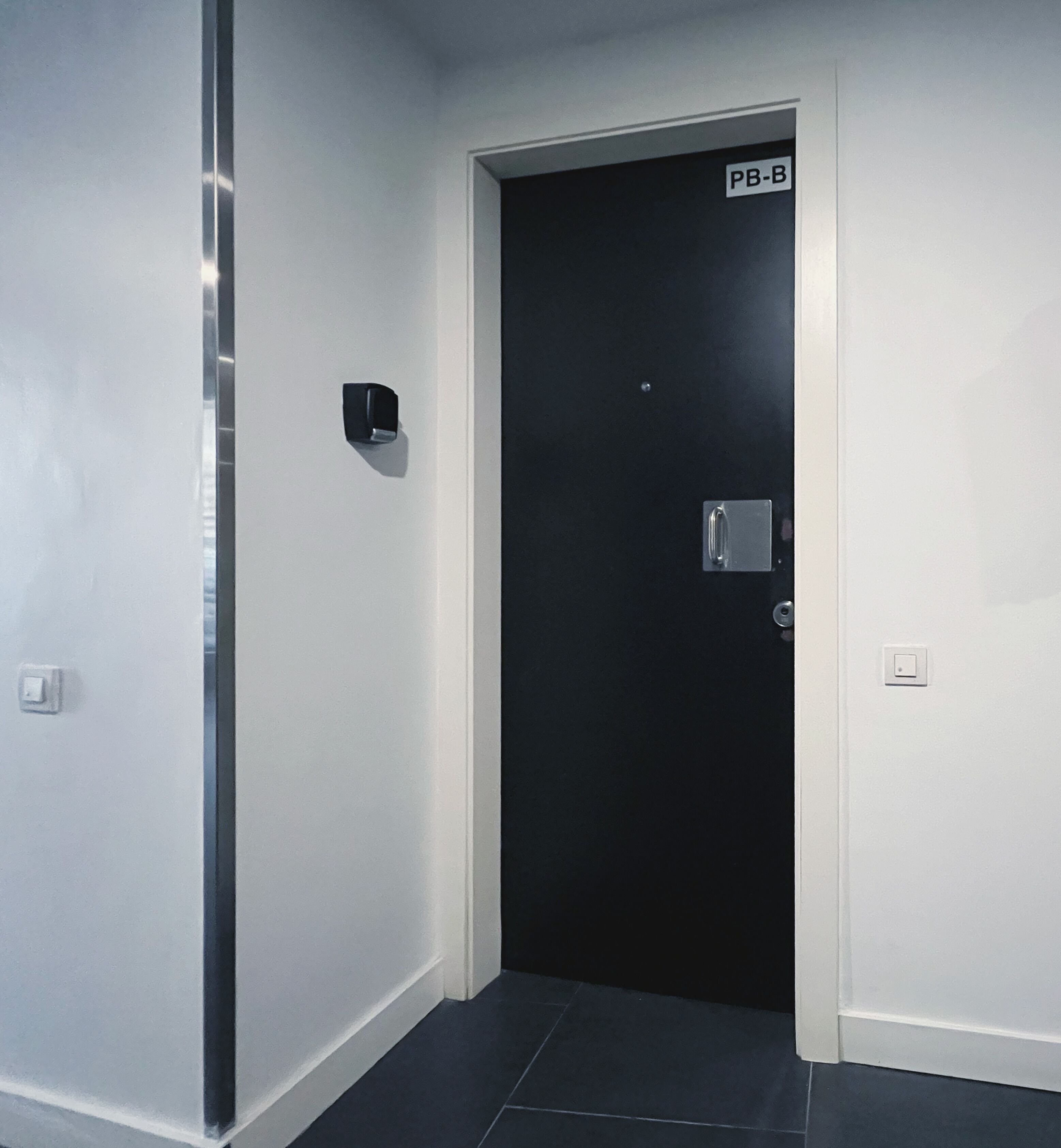 A hallway with a black door labeled "PB-B".