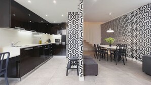 Una cocina moderna con armarios negros, una encimera blanca y una zona de comedor con un papel tapiz estampado.