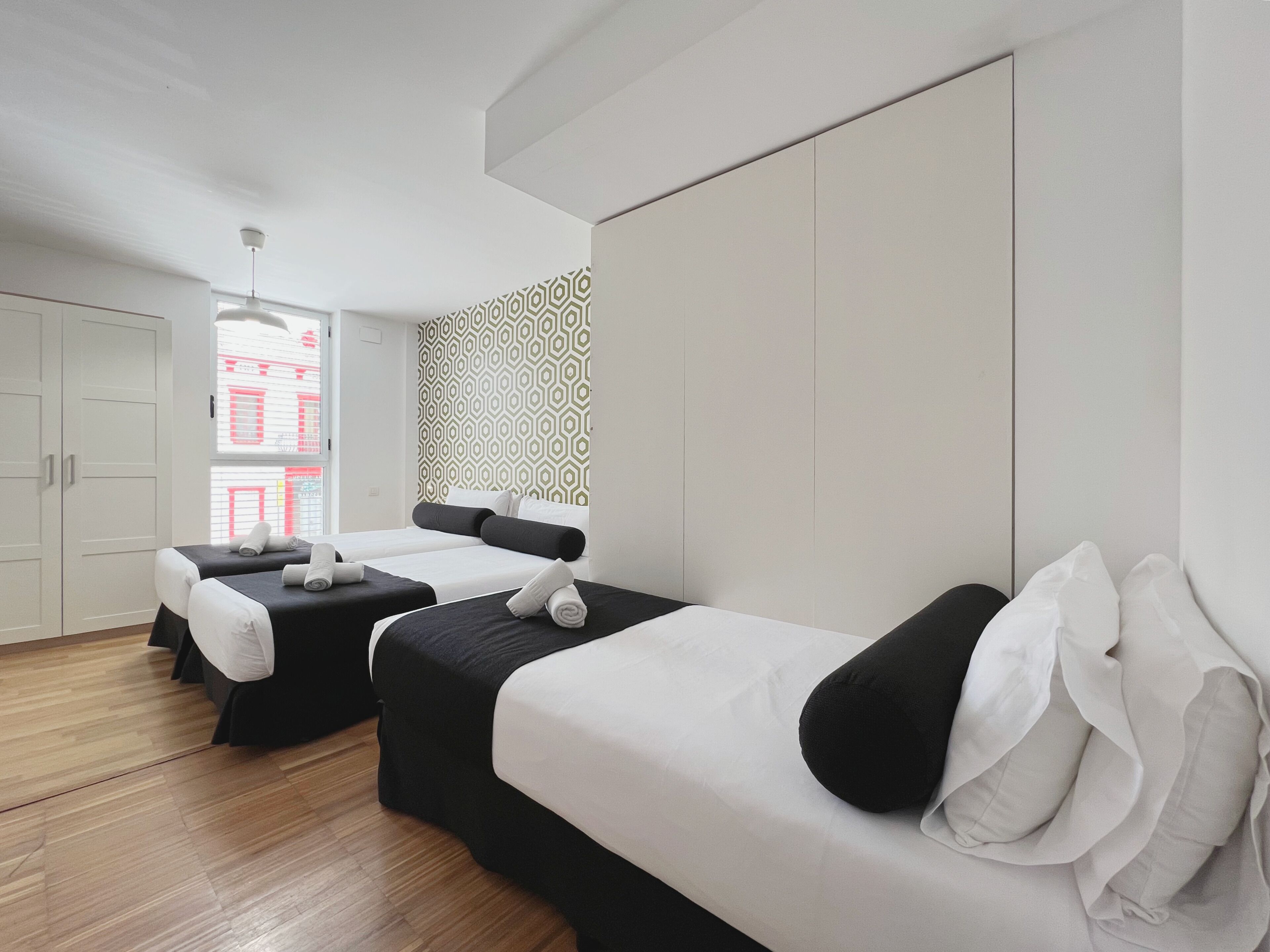 Ein modernes Hotelzimmer mit zwei Betten, einem Kleiderschrank und einer Wand mit Muster.