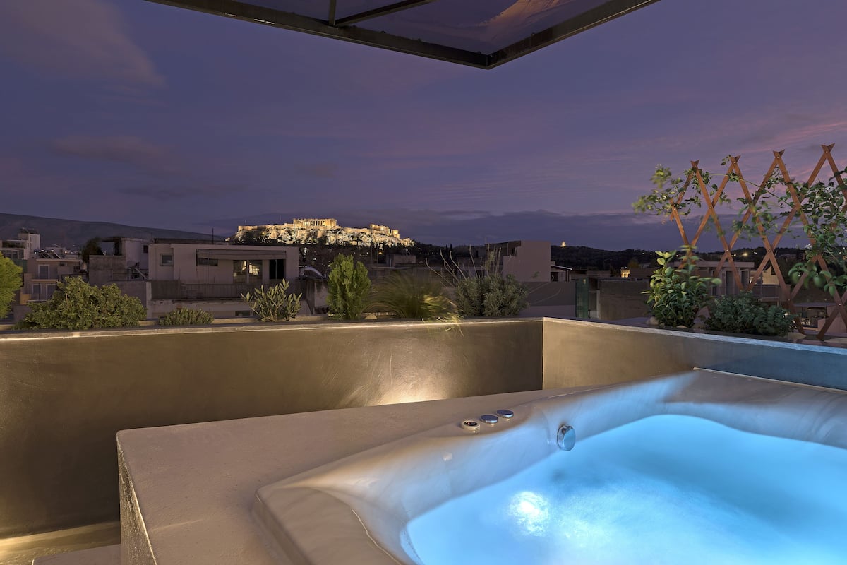 A rooftop hot tub with a view of a cityscape at dusk.