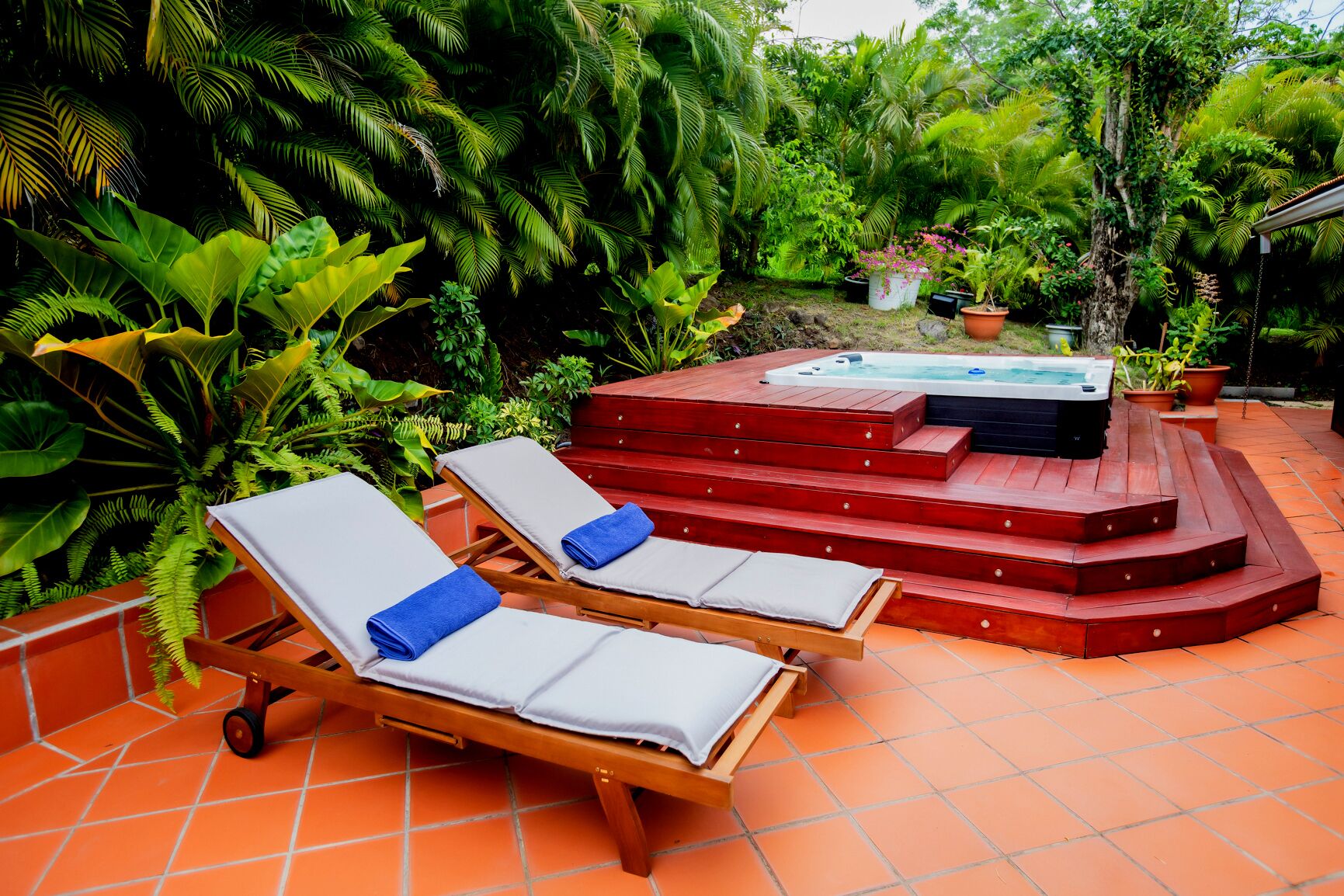 A hot tub area with steps leading up to it, surrounded by lush greenery.