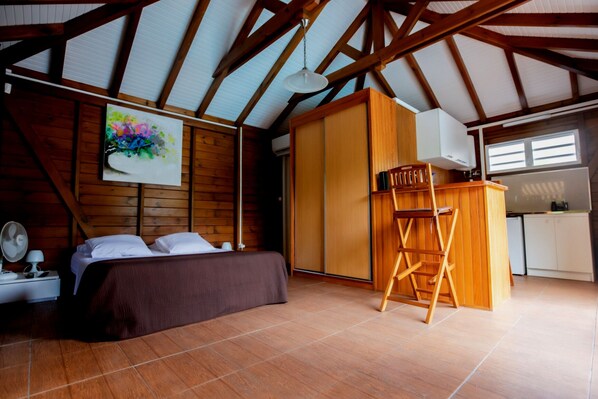 A bedroom with a bed, a desk, a chair, and a painting on the wall.